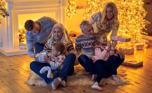 Mutlu Noeller ve mutlu yeni yıl! Mutlu aile kutluyor kış tatili evde. Büyükanne ve büyükbaba, ebeveynler ve çocuklar birlikte dekore edilmiş yılbaşı ağacının yanında otururken Noel için bekliyor