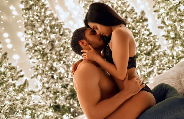 Mutlu Noeller ve mutlu yeni yıl! Seksi tutkulu çift birlikte Noel kutluyor. Çekici kadın iç çamaşırı ve sakallı yakışıklı bir şekilde dekore edilmiş yılbaşı ağaçları arka plan üzerinde seks.