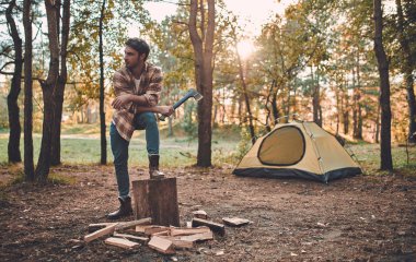 Erkek turist yeni yerler keşfetmek. Sakallı yakışıklı niteliğine. Balta ve turistik çadır yakınındaki yakacak odun adam. Oduncu