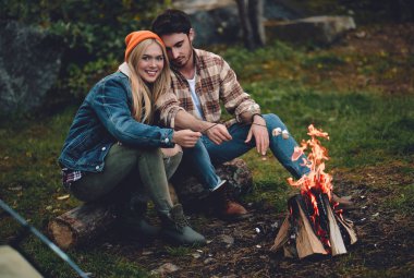 Turist genç çift yeni yerler keşfediyoruz. Çekici kadın ve yakışıklı adam birlikte doğa üzerinde vakit. Şenlik ateşi ve orman ve hatmi yapmak turistik çadırda yakın oturan.