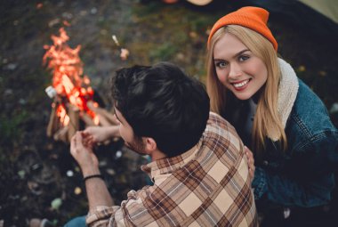 Turist genç çift yeni yerler keşfediyoruz. Çekici kadın ve yakışıklı adam birlikte doğa üzerinde vakit. Şenlik ateşi ve orman ve hatmi yapmak turistik çadırda yakın oturan.