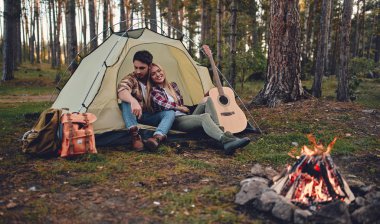 Genç çift turist birlikte yeni yerler keşfetme eylemi. Çekici genç kadın ve yakışıklı sakallı adam birlikte doğa üzerinde vakit. Ormandaki turistik çadırda şenlik ateşi yakın oturan.