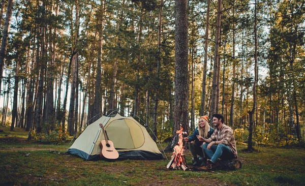 Turist genç çift yeni yerler keşfediyoruz. Çekici kadın ve yakışıklı adam birlikte doğa üzerinde vakit. Şenlik ateşi ve orman ve hatmi yapmak turistik çadırda yakın oturan.