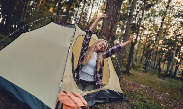 Female tourist exploring new places. Attractive young woman spending time on nature. Waking up in touristic tent in forest.