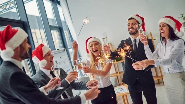 Merry Christmas and Happy New Year! Group of office workers celebrating winter holidays together at work. Business people drinking champagne in office.