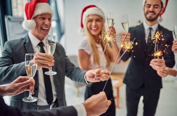 Merry Christmas and Happy New Year! Group of office workers celebrating winter holidays together at work. Business people drinking champagne in office.