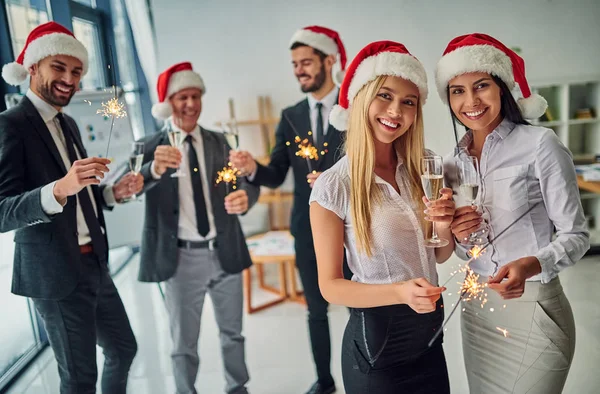 Merry Christmas and Happy New Year! Group of office workers celebrating winter holidays together at work. Business people drinking champagne in office.