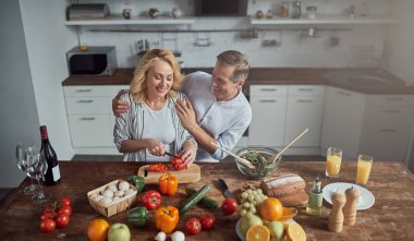 Üst düzey çift mutfak yemek pişiriyor. Güzel kadın ve yakışıklı adam birlikte evde vakit. Sağlıklı yaşam tarzı kavramı.