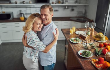 Üst düzey çift mutfak yemek pişiriyor. Güzel kadın ve yakışıklı adam birlikte evde vakit. Sağlıklı yaşam tarzı kavramı.