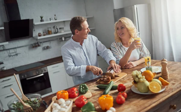Senior couple is cooking on kitchen. Beautiful woman and handsome man are spending time together at home. Healty lifestyle concept.