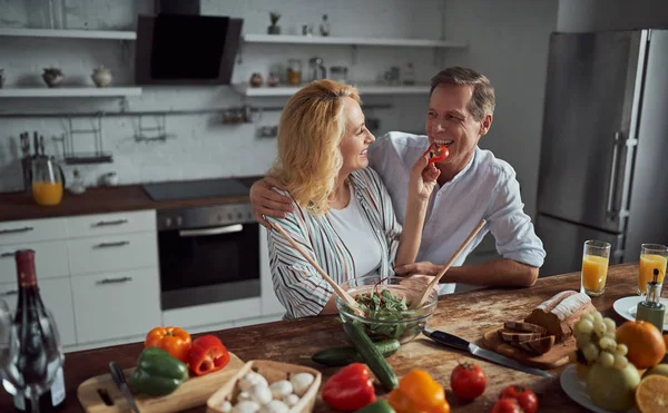 Senior couple is cooking on kitchen. Beautiful woman and handsome man are spending time together at home. Healty lifestyle concept.