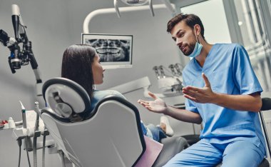 Erkek dişçi ile stomatoloji kliniğinde çekici genç bir kadın. Sağlıklı diş konsepti.