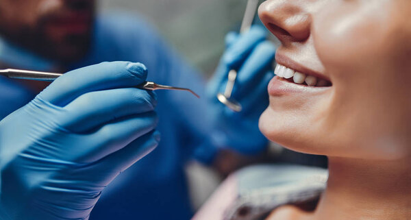 Attractive young woman in stomatology clinic with male dentist. Healthy teeth concept.