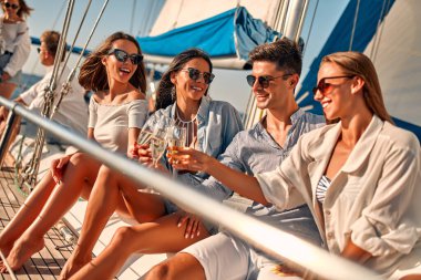 Lüks bir yatta rahatlayıp şampanya içen bir grup arkadaş. Denizde yelken açarken eğleniyorduk. Seyahat ve yat konsepti.