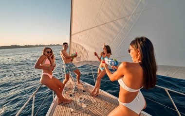 Lüks bir yatta dinlenen bir grup arkadaş. Denizde yelken açarken su tabancalarıyla eğleniyorlar. Seyahat ve yat konsepti.