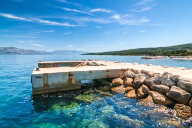 Concrete pier for ships in the Supetar harbor on the Brac island at a summer, Croatia, Europe. clipart