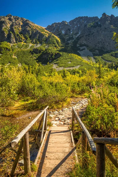 Drewniany most na pierwszym planie górskiego krajobrazu jesienią. — Zdjęcie stockowe
