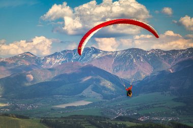 Slovakya 'nın kuzeyindeki Zilina havzasının dağlık manzarası üzerinde Stranik tepesinden uçan paraglider.