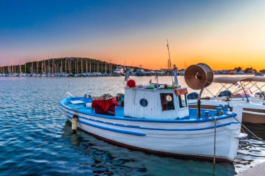 Limandaki eski balıkçı teknesi. Hırvatistan, Avrupa 'daki Adriyatik Denizi' nin Dalmaçya kıyısındaki popüler bir turizm beldesi olan Rogoznica köyünde, deniz kıyısında gün batımı. 
