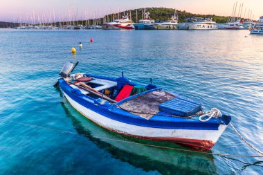 Limandaki eski balıkçı teknesi. Hırvatistan, Avrupa 'daki Adriyatik Denizi' nin Dalmaçya kıyısındaki popüler bir turizm beldesi olan Rogoznica köyünde, deniz kıyısında gün batımı. 