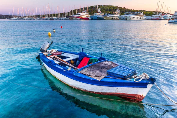 Limandaki eski balıkçı teknesi. Hırvatistan, Avrupa 'daki Adriyatik Denizi' nin Dalmaçya kıyısındaki popüler bir turizm beldesi olan Rogoznica köyünde, deniz kıyısında gün batımı. 