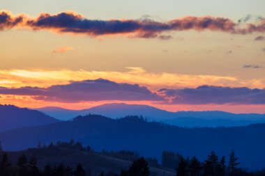 Pastel turuncu renkler ve mor bulutlarla dolu parlak bir gün doğumu gökyüzü..