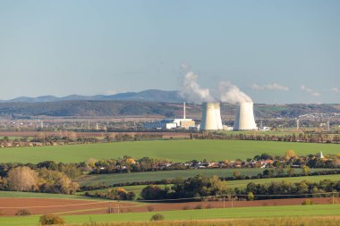 Nükleer enerji santrali çevreye yerleşmiş. Uzakta kayan tepeler ve tarlalar enerji üretiyor..