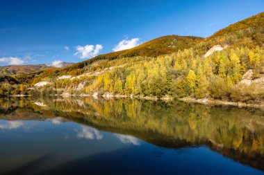 Göldeki renkli tepelerin yansımasıyla sonbahar manzarası. Slovakya, Avrupa 'daki Sutovo köyü yakınlarındaki taş ocağını su bastı.