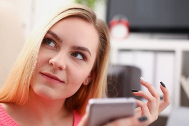 Genç sarışın womansit kanepe tutun Smartphone elinde güzel