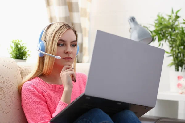 Jovem bela mulher loira sentar-se no sofá na sala de estar segurar laptop nos braços ouvir música — Fotografia de Stock