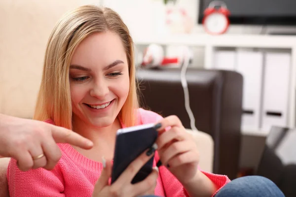 Jovem bonita loira womansit no sofá segurar smartphone em mãos — Fotografia de Stock