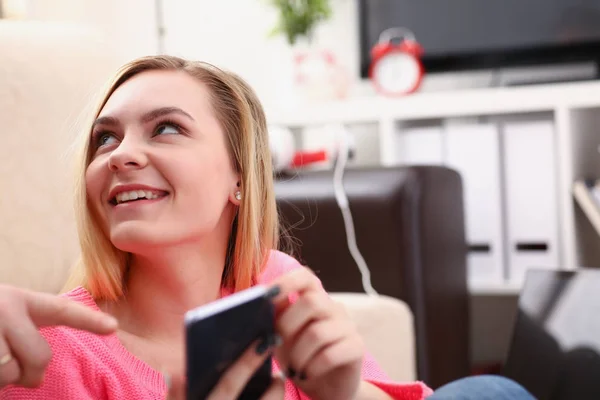 Jovem bonita loira womansit no sofá segurar smartphone em mãos — Fotografia de Stock