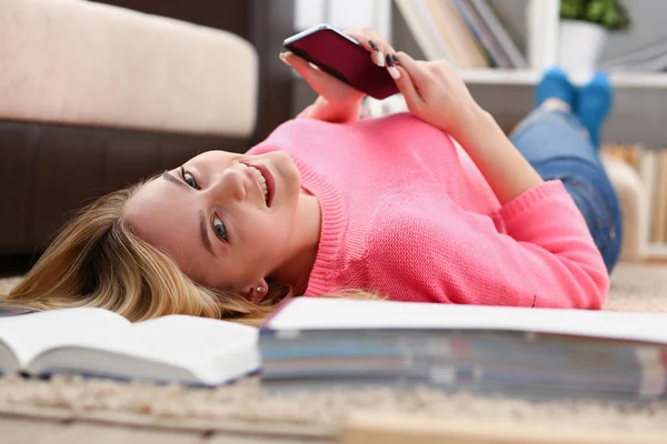 Young beautiful woman have a rest lie on the floor hold smartphone in arms — Stock Photo, Image