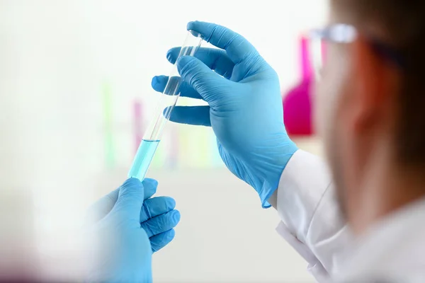 A male chemist holds test tube of glass in — Stock Photo, Image