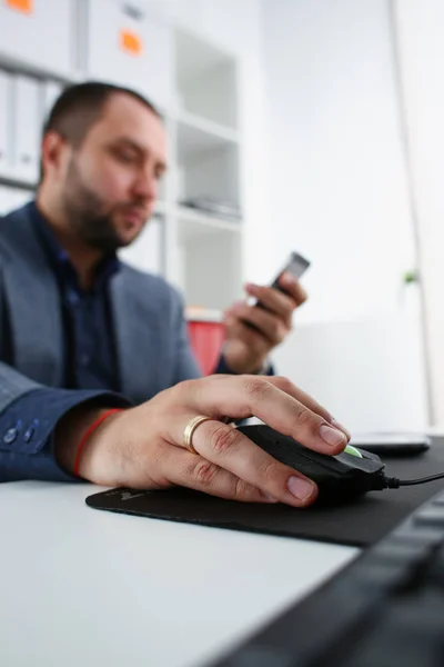 Zakenman werk op computer houden muis in arm en mobiele telefoon in andere closeup — Stockfoto