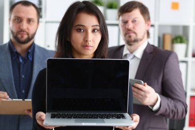 Genç başarılı businesslady portresi ofiste dizüstü bilgisayar ve iki iş adamları tutun