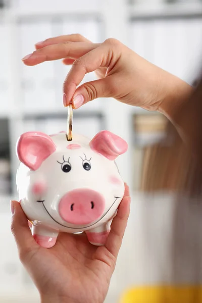 Mujer mano poner moneda en divertido sonrisa piggybank —  Fotos de Stock