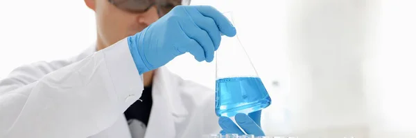 A male chemist holds test tube of glass in — Stock Photo, Image