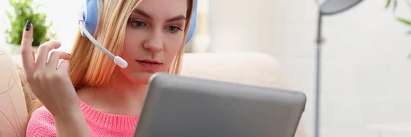 Jovem bela mulher loira sentar-se no sofá na sala de estar segurar tablet nos braços ouvir música ensolarada — Fotografia de Stock