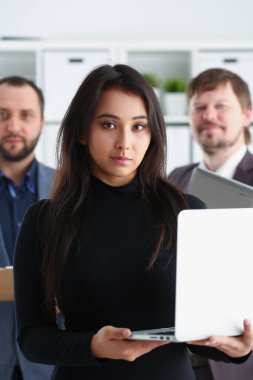 Genç başarılı businesslady portresi ofiste dizüstü bilgisayar ve iki iş adamları tutun