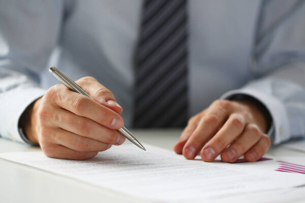 Hand of businessman in suit filling and signing with
