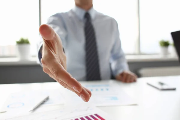 Man in suit and tie give hand as hello in office closeup