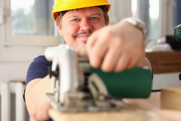 Arms of worker using electric saw closeup