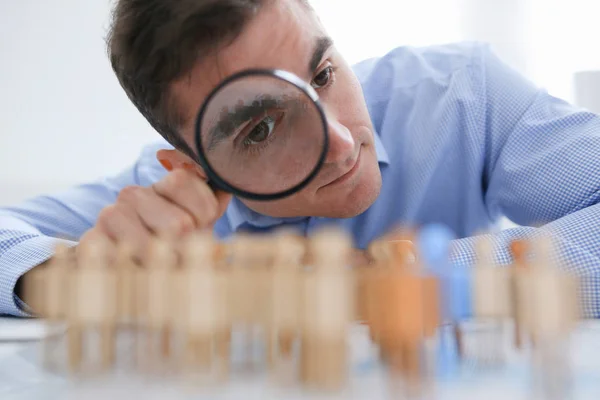 A businessman in blue shirt is holding a magnifying glass — Stock Photo, Image