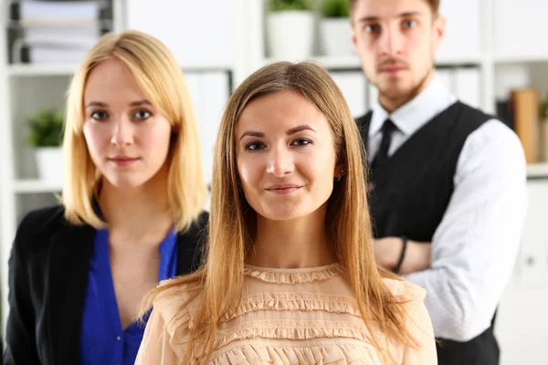 Group of smiling people stand in office looking in camera