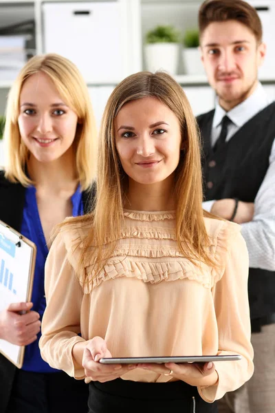 Group of smiling people stand in office looking in camera