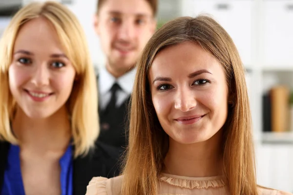 Group of smiling people stand in office looking in camera