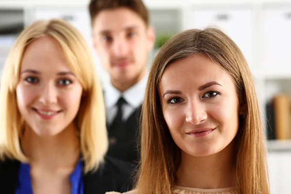 Group of smiling people stand in office looking in camera