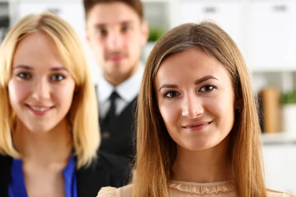 Group of smiling people stand in office looking in camera