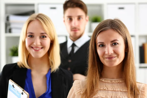 Group of smiling people stand in office looking in camera